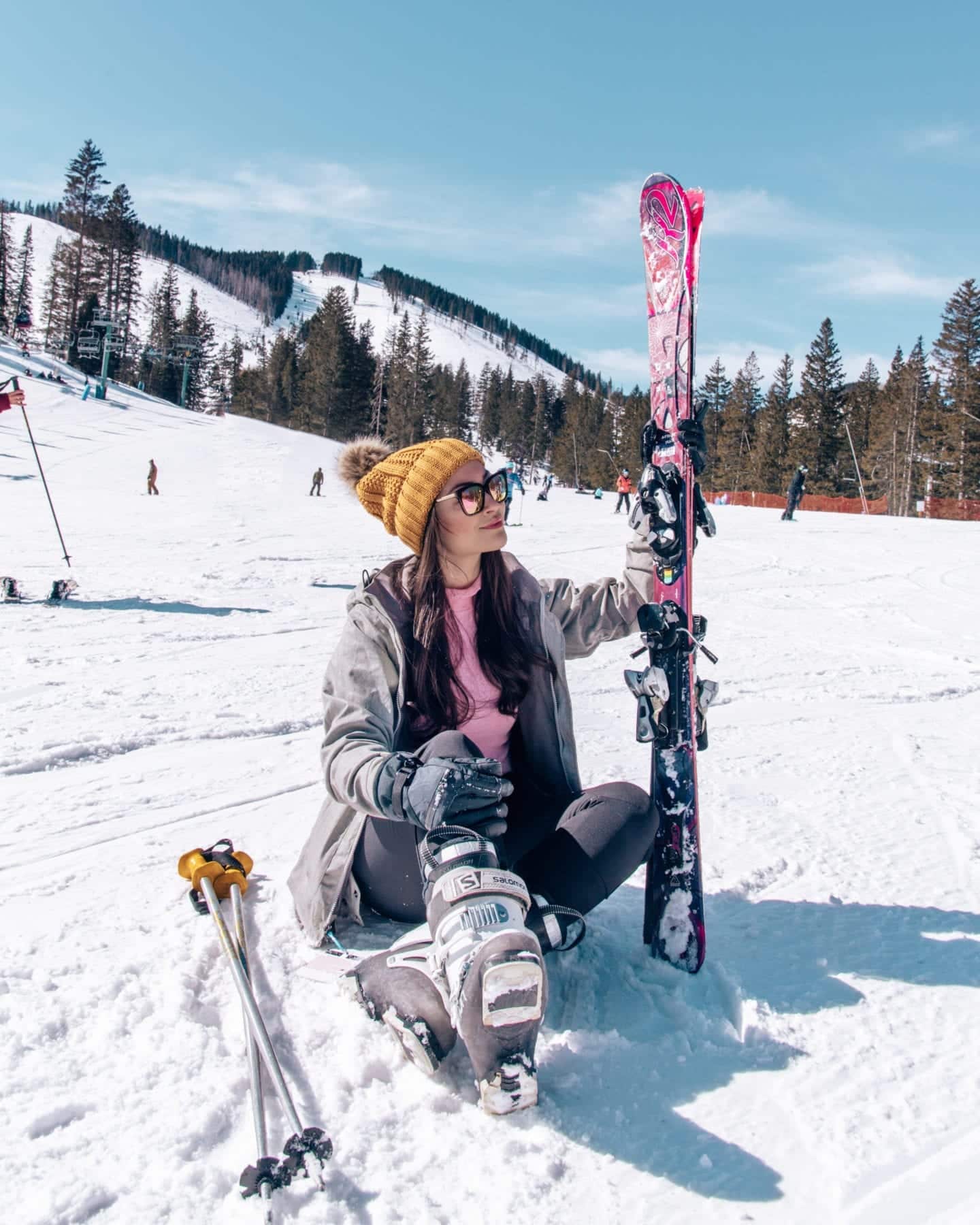 girl sitting on snow holding skis