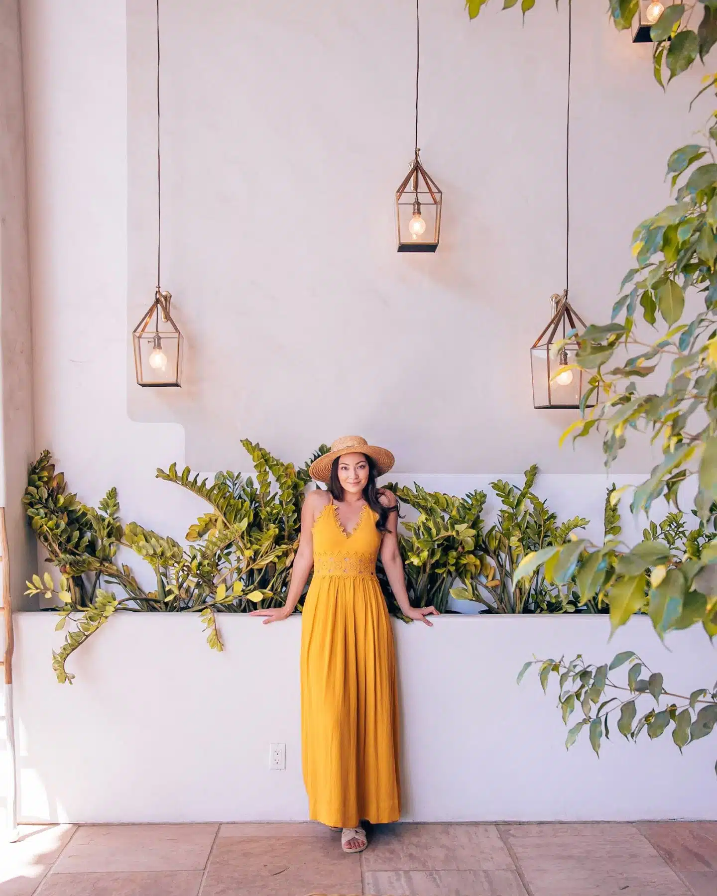 girl in front of white wall with plants and lights