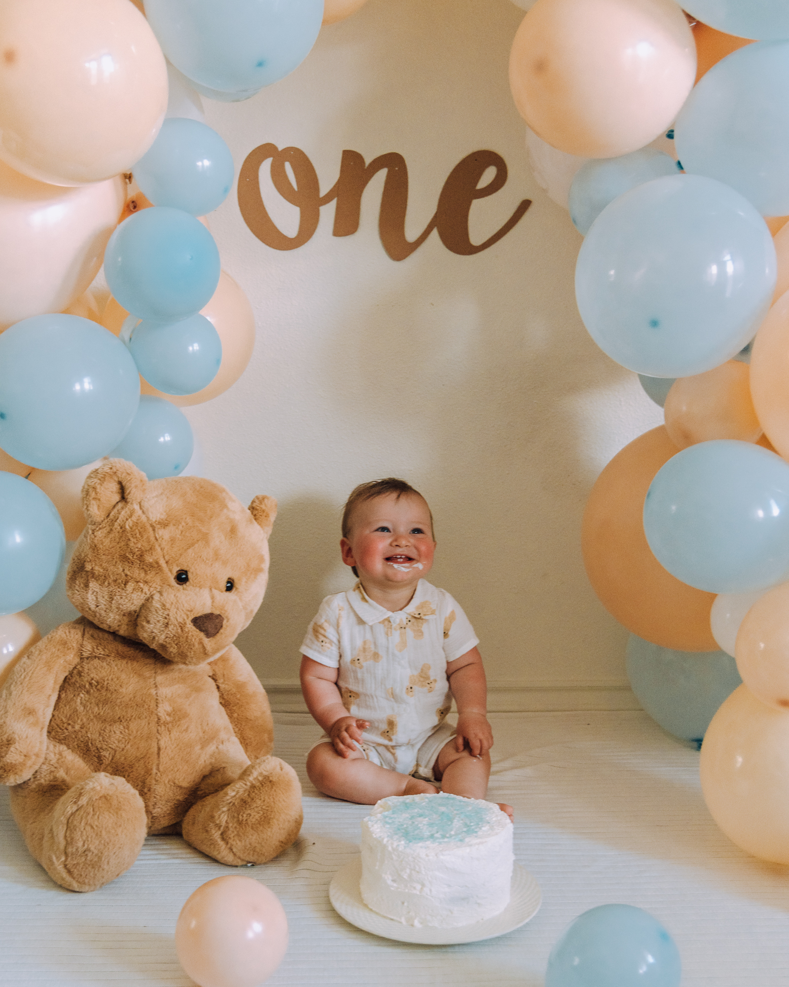 Baby one year birthday cake smash idea for a baby spring photoshoot with pastel colors and a teddy bear theme.