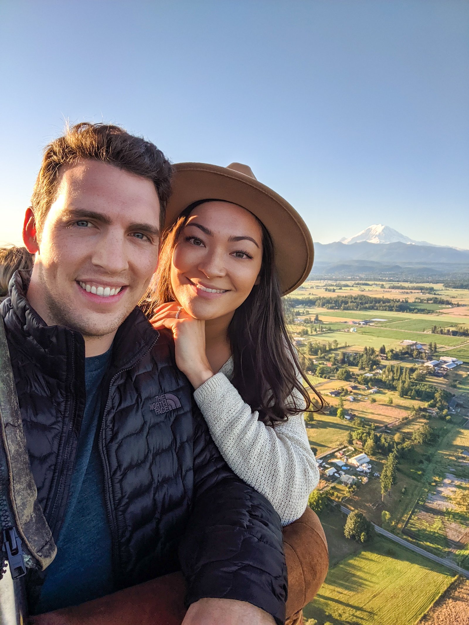 Couple taking a selfie from a hot air balloon ride with Mount Rainier in the background.