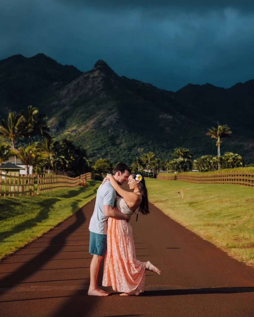 Couple poses for photo on an Instagrammable photo spot in Kauai: a road with dramatic mountain views.