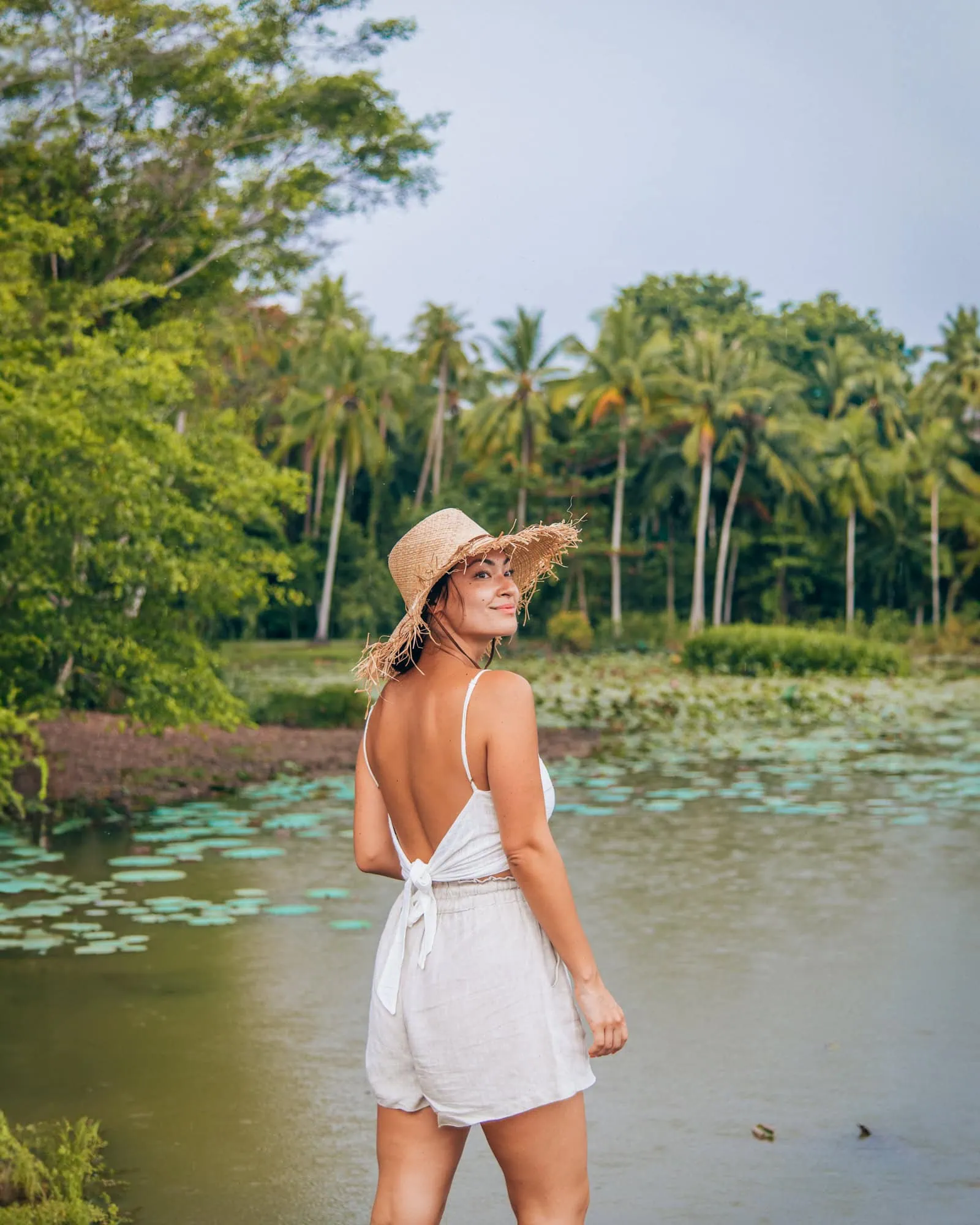 Girl wearing a straw hat in front of a lake on Pulau Ubin, Singapore